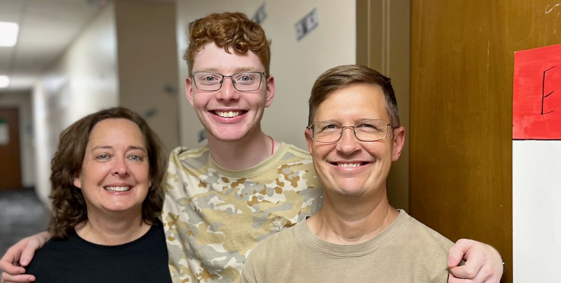 student with parents in hallway of his residence hall